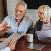 Happy aged couple consulting with insurance agent at home Como se aposentar junto ao INSS? Confira 5 dicas práticas!